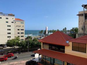 a building with a red roof with the ocean in the background at Cozy Private Room in El Malecn, Santo Domingo in Santo Domingo