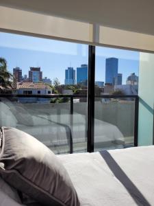 1 cama con almohada frente a una ventana en Confortable y luminoso apto. a pasos del mar., en Montevideo