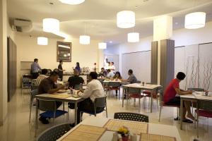 a group of people sitting at tables in a restaurant at Cordela Inn HM Yamin Medan in Medan