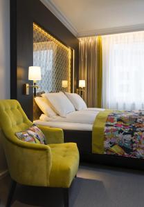 
a hotel room with a bed, chair, lamp and window at Thon Hotel Rosenkrantz Oslo in Oslo
