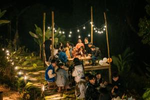 a group of people sitting around a table at night at MiCasa - Nhà gác mái trên đỉnh đồi in Cao Bằng