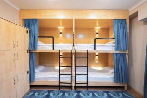 2 łóżka piętrowe w pokoju z niebieskimi zasłonami w obiekcie Kaganat Hostel w mieście Biszkek