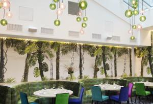 a restaurant with tables and chairs and palm trees at Thon Hotel Rosenkrantz Oslo in Oslo