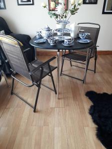 einem schwarzen Tisch mit zwei Stühlen und einem Tisch mit Geschirr darauf in der Unterkunft Room in Apartment - 1 Bedroom In A Homely Home With A Lovely Farm 