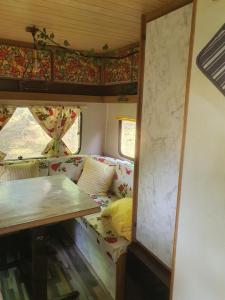 een kamer met een bank en een tafel in een trein bij Koppány Pines Rewild Escapes - Vintage Caravan in Koppányszántó