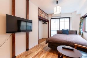 a bedroom with a bed and a flat screen tv at Omotenashi House Kawaguchi in Kawaguchi