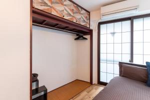 sypialnia z łóżkiem i dużym oknem w obiekcie Omotenashi House Kawaguchi w mieście Kawaguchi