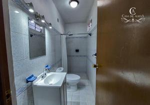 a bathroom with a white toilet and a sink at Casa de Alicia Habitación Monte Albán in Oaxaca City