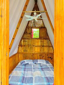 Bett in einem strohgedeckten Zelt mit Fenster in der Unterkunft Jodels Paradise in Ligao