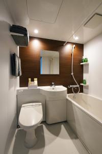 ein Badezimmer mit einem WC, einem Waschbecken und einer Badewanne in der Unterkunft SKI INN HAKUBA in Otari