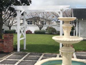 een witte pergola en een fontein in een tuin bij Grand On Victoria in Hawera