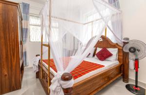 a bedroom with a wooden bed with a canopy at Uroa Beach Lodge in Uroa