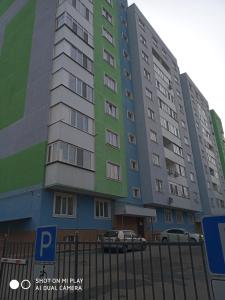 um edifício alto com um carro estacionado em frente em Современная квартира с видом на горы em Almaty