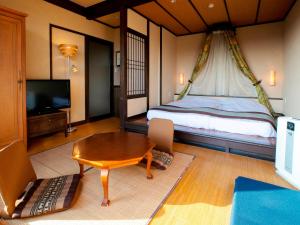 a bedroom with a bed and a table and a television at Ijika Daiichi Hotel Kagura in Toba