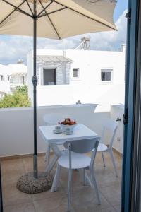 a white table with a bowl of fruit and an umbrella at Naxian Place in Agios Prokopios