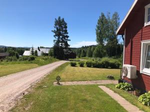 a dirt road next to a red house with a window at Trevlig stuga nära Hovfjället in Torsby