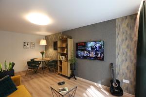 a living room with a couch and a guitar on a wall at Modern 2 Room Apartment - FREE PARKING - NETFLIX in Alytus