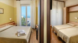 a hotel room with two beds and a balcony at Hotel Boston in Cattolica