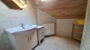 bagno con lavandino bianco e soffitto in legno di Apartment in Zamardi/Balaton 20369 a Zamárdi