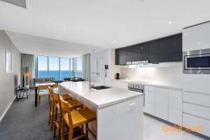 une cuisine avec des placards blancs et une table avec des chaises dans l'établissement Gold Coast Private Apartments - H Residences, Surfers Paradise, à Gold Coast
