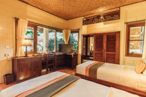a bedroom with two beds and a desk with a computer at Munari Resort Ubud in Ubud