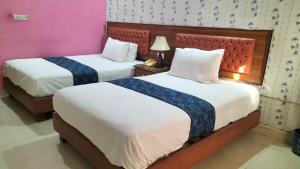 a bedroom with two beds with white sheets and purple walls at Hotel Rest INN in Lahore +15 photos