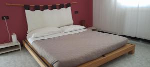 un grande letto in una stanza con una parete rossa di B&B Villa Grace a Città Sant'Angelo