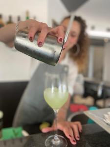 une femme verse un verre de vin blanc dans l'établissement Hotel Gardenia Fiera, à Cermenate