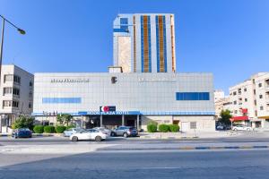 a large building with cars parked in a parking lot at Capital O 125 Moon Plaza Hotel in Manama