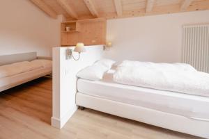 a white bedroom with a bed and a couch at Garnì Aurora Bed and Breakfast in Soraga