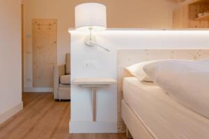 a bedroom with a bed and a lamp and a chair at Garnì Aurora Bed and Breakfast in Soraga