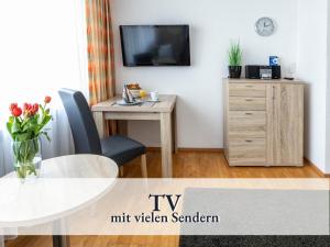 a living room with a table and a tv on a wall at Schicke Ferienwohnung in bester Bodenseelage l 1 Minute zum Bodensee l 1 Zimmer l Vollausgestattete Küche l Free-WLAN l Willkommen im Apartment Stahringen in Radolfzell am Bodensee
