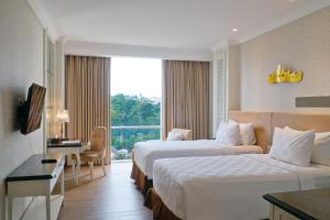 um quarto de hotel com duas camas e uma janela em Swiss-Belhotel Lampung em Bandar Lampung