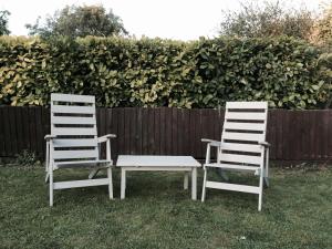 deux chaises blanches assises dans l'herbe à côté d'une clôture dans l'établissement Kendall Lodge, à Burwell