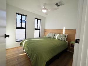 um quarto com uma cama verde e 2 janelas em Ardrossan Caravan Park em Ardrossan