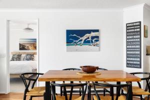 uma sala de jantar com uma mesa de madeira e cadeiras em 5 Pacific Outlook Ocean View Apartment in Sunshine Beach em Sunshine Beach