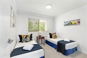 a bedroom with two beds and a table at 5 Pacific Outlook Ocean View Apartment in Sunshine Beach in Sunshine Beach