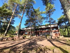a building in the woods with trees in the foreground at Sea Hotel Mäntyniemi in Siltakylä