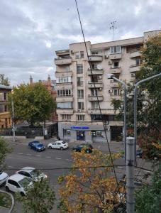 a large building with cars parked in a parking lot at Tudor's apartment in Bucharest