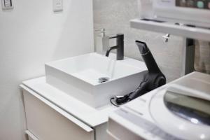 a white bathroom sink with a black phone on it at Pufuka Inn Skytree in Tokyo