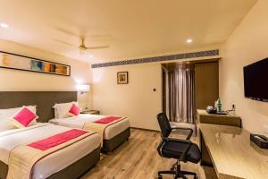 a hotel room with two beds and a flat screen tv at Quality Inn Ramachandra in Visakhapatnam