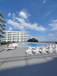 a row of lounge chairs on a deck next to the beach at Apartament Sapphire Rogowo Pearl in Mrzeżyno