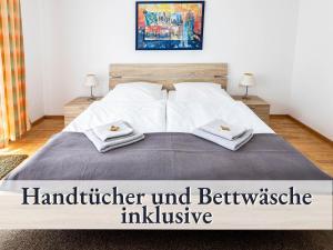 una camera da letto con un letto e due asciugamani di Große moderne Ferienwohnung in bester Bodenseelage l 1 Minute zum Bodensee l 2 Zimmer l Vollausgestattete Küche l Sonnenbalkon l WLAN l Willkommen im Apartment Güttingen a Radolfzell am Bodensee