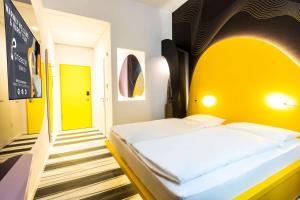 a bedroom with a bed with a yellow headboard at Prize by Radisson, Bonn City in Bonn