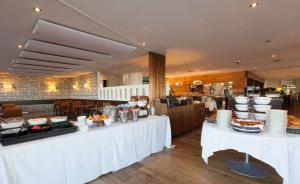 een restaurant met witte tafels met eten erop bij Best Western Premier Hotel Beaulac in Neuchâtel