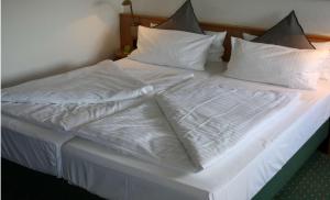 uma cama branca com lençóis e almofadas brancos em Best Western Spreewald em Lübbenau