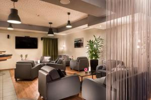 una sala de espera con sofás, sillas y TV en Best Western Hotel Dortmund Airport, en Dortmund