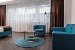 a hotel room with two blue chairs and a bed at Best Western Hotel Dortmund Airport in Dortmund