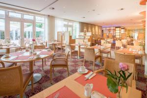 un restaurante con mesas, sillas y ventanas en Best Western Premier Castanea Resort Hotel, en Lüneburg