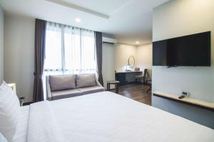 a hotel room with a bed and a couch and a window at SureStay Plus by Best Western Sukhumvit 2 in Bangkok +112 photos